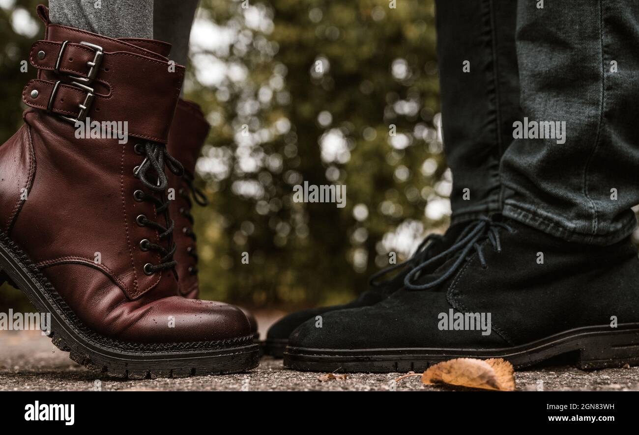Feet of couple. Man and woman is standing opposite each other. Close-up of blue suede shoes and burgundy leather boots on tiptoe. Close-up. Stock Photo