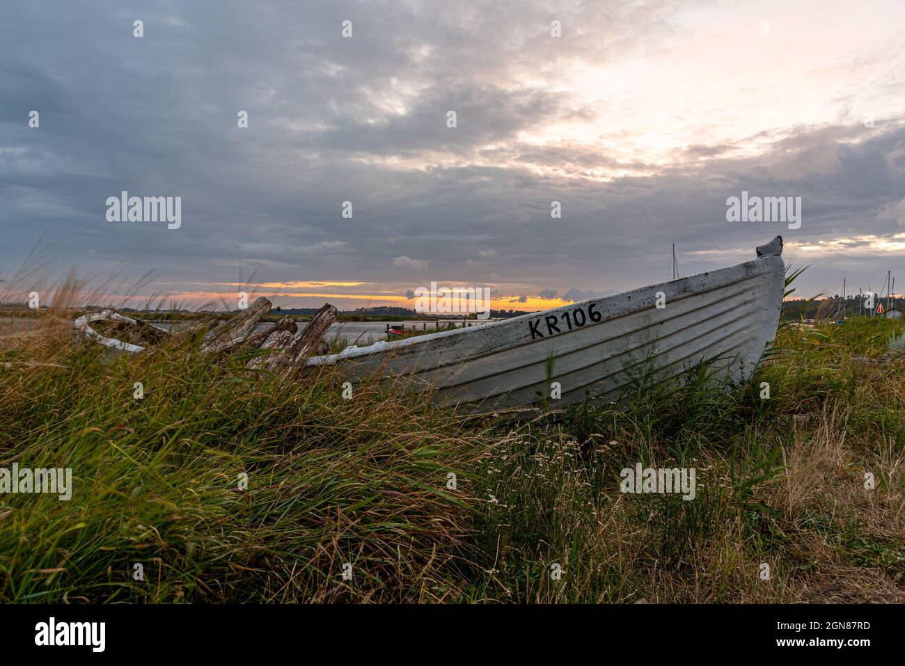an old wrecked rowboat on the shore, overgrown with grass in the sunset, Bisserup, Denmark, August 8, 2021 Stock Photo