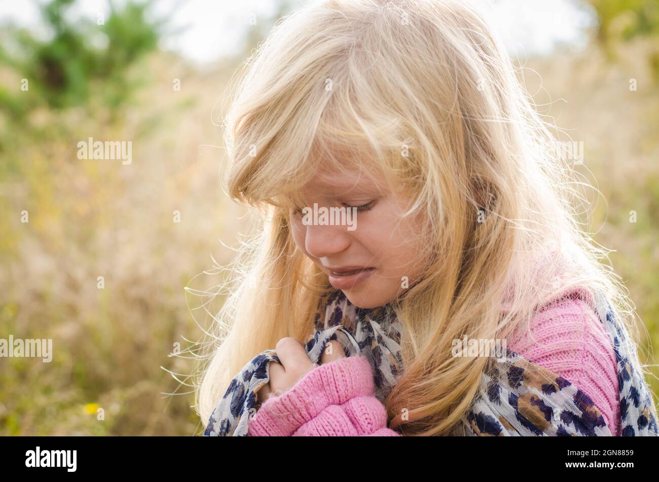 little lovely girl with long blond hair crying alone in autumn nature Stock Photo