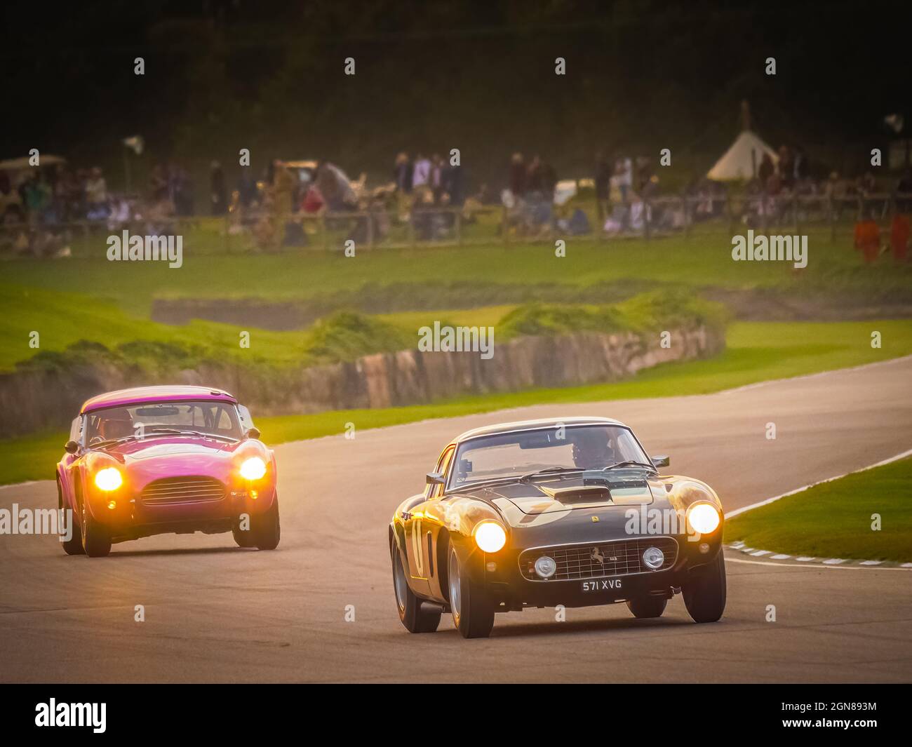Ferrari 250 and a Cobra racing at sunset at the Goodwood Revival 2021, West Sussex, uk Stock Photo