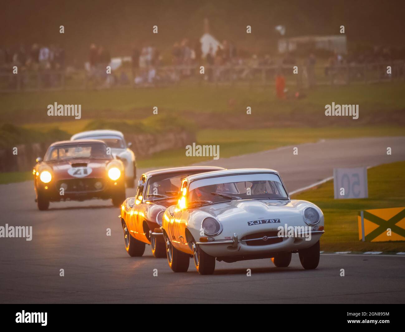 E Type Jaguars and Ferrari 250 racing at sunset at the Goodwood Revival 2021, West Sussex, uk Stock Photo