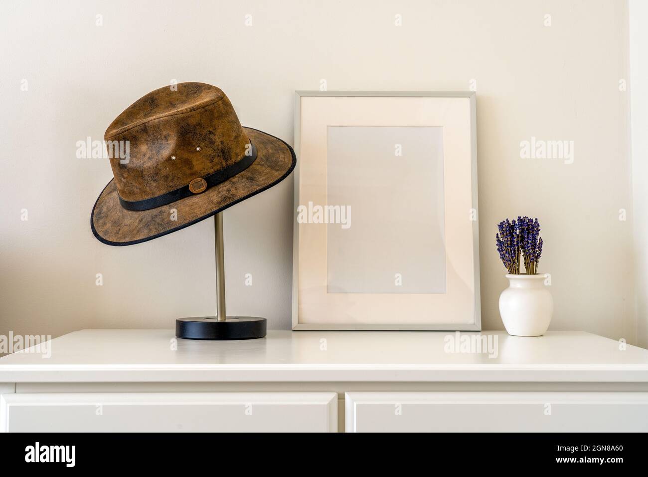 Interior design mockup with silver photograph frame with mount , vase with lavender and a leather hat Stock Photo