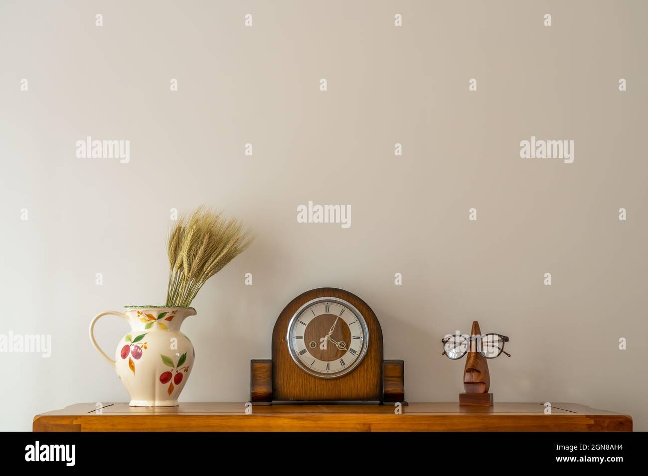 still life of antique clock with floral jug and optical prescription