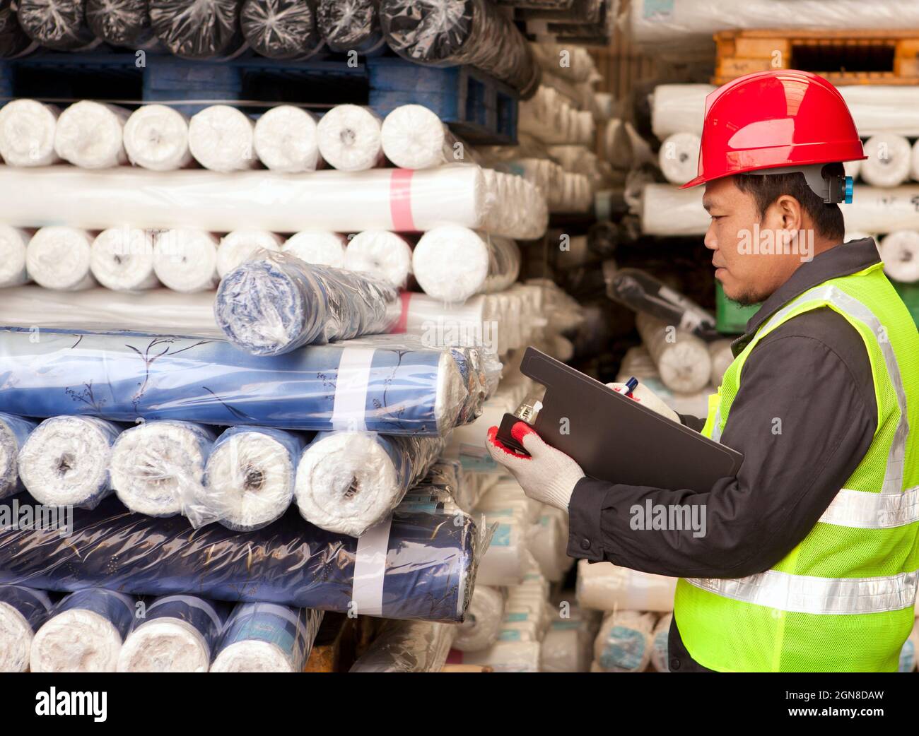 Textile factory foreman auditing raw material fabrics in warehouse