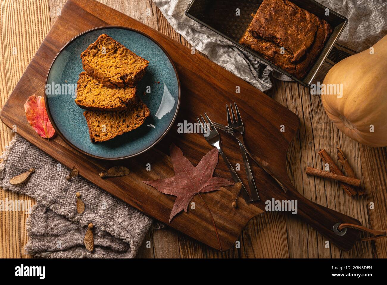 Sliced pieces of vegan sweet and spicy pumpkin cake on wooden cutting board and rustic table. Traditional treat in autumn for Thanksgiving, Halloween. Stock Photo