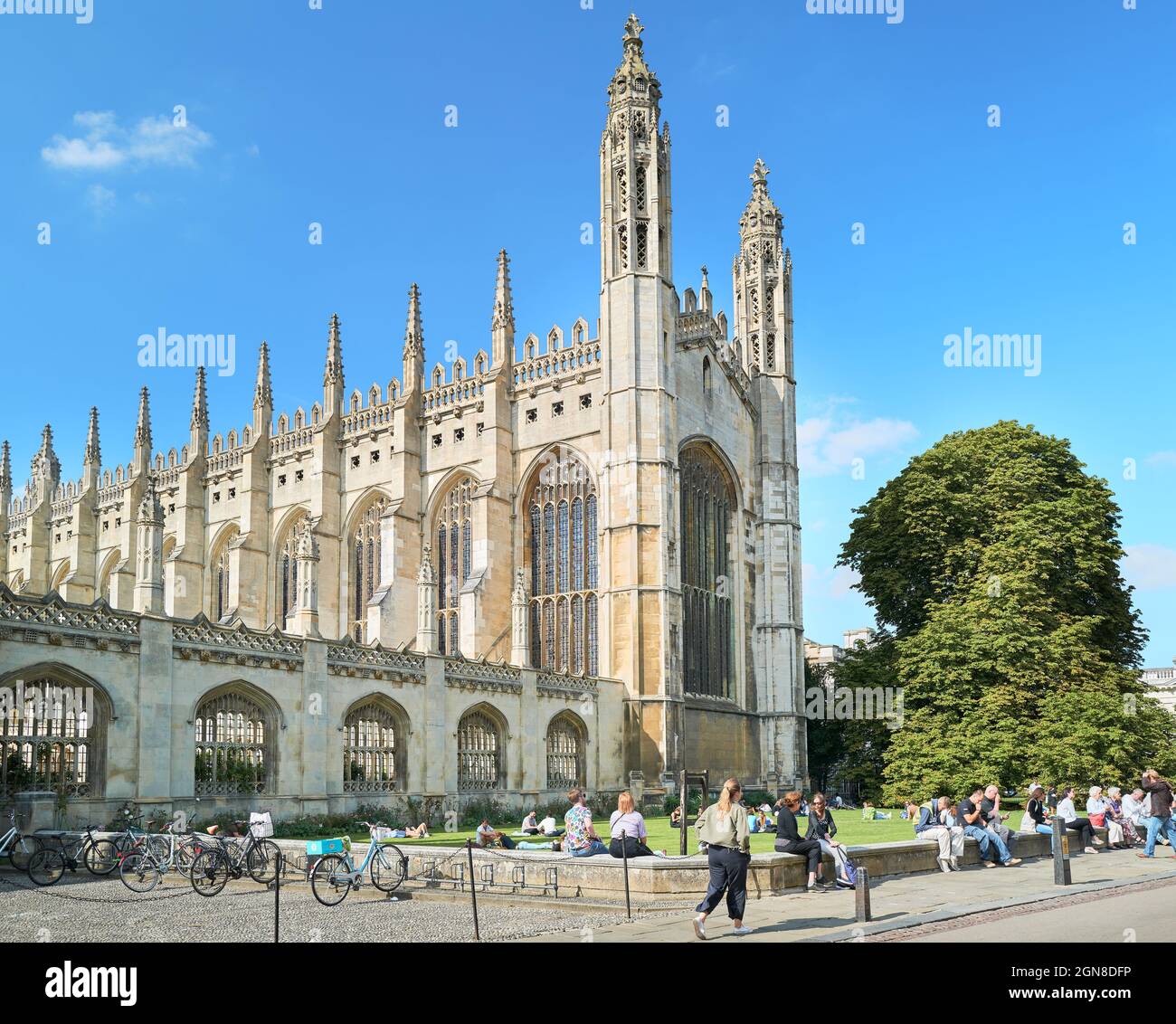 Many tourists sit and relax on the low wall outside the chapel of King's college, university of Cambridge, England, on a sunny summer day. Stock Photo