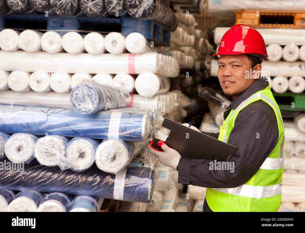 Textile factory foreman checking raw material fabrics in warehouse
