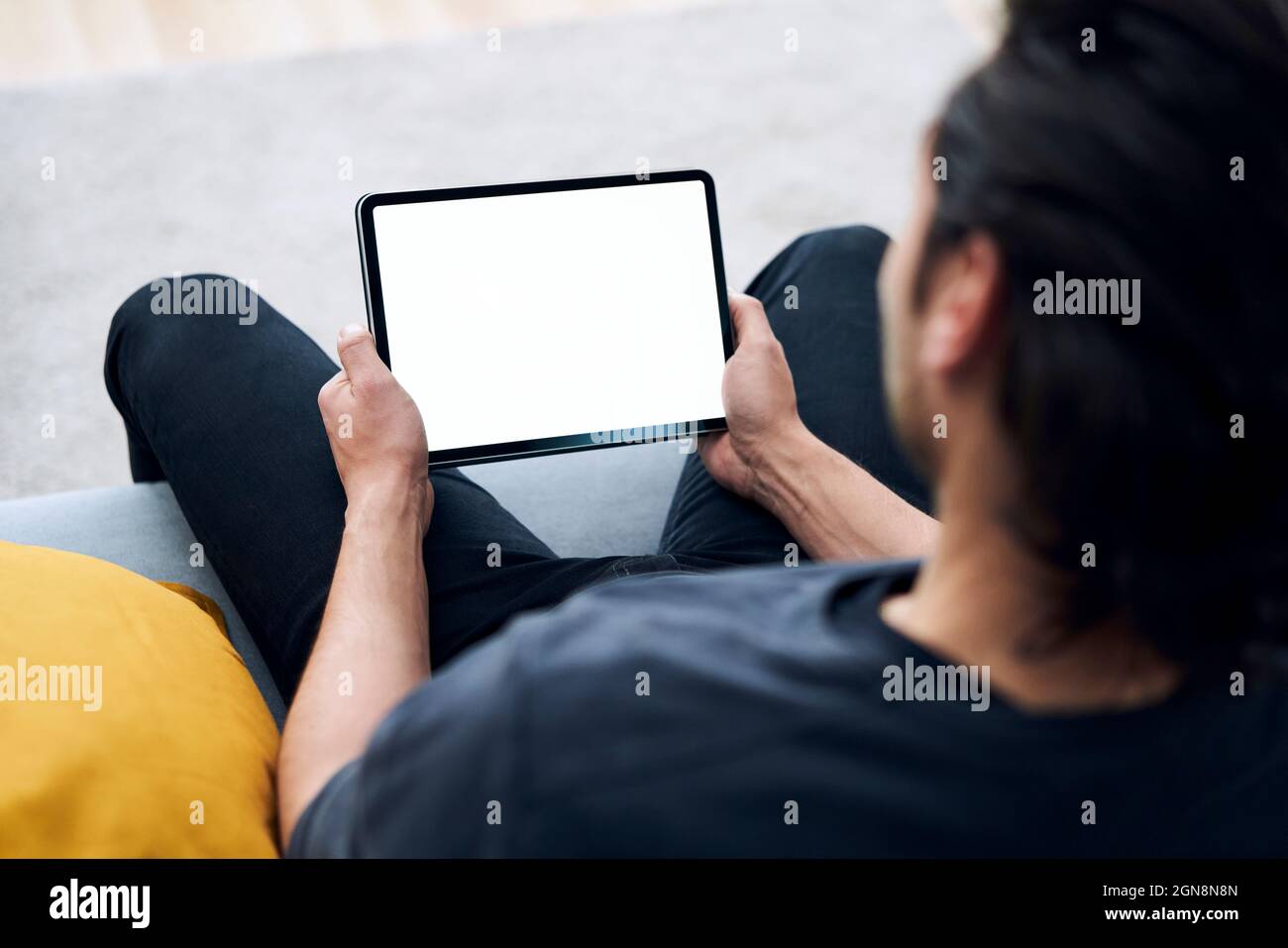 Young man holding digital tablet while sitting on sofa Stock Photo