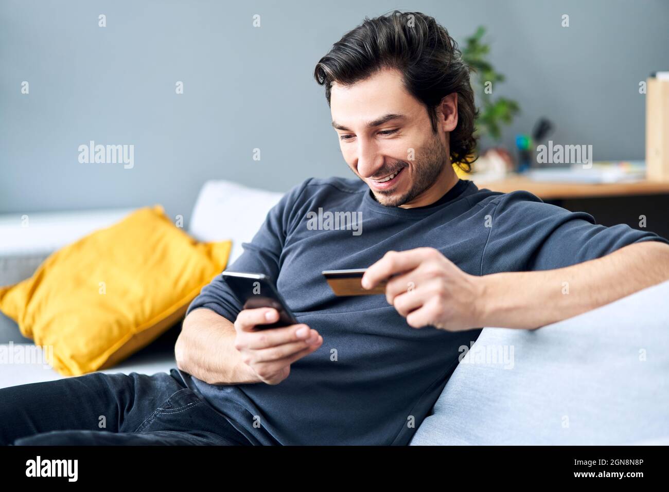 Man using smart phone while making payment through credit card at home Stock Photo