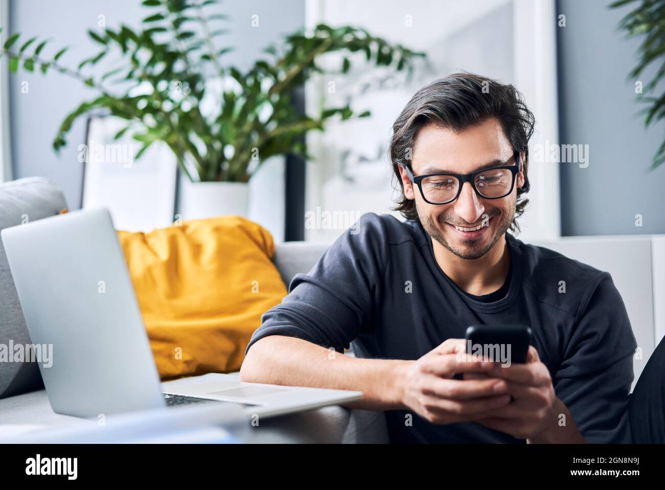 Male freelance worker using smart phone while working at home Stock Photo