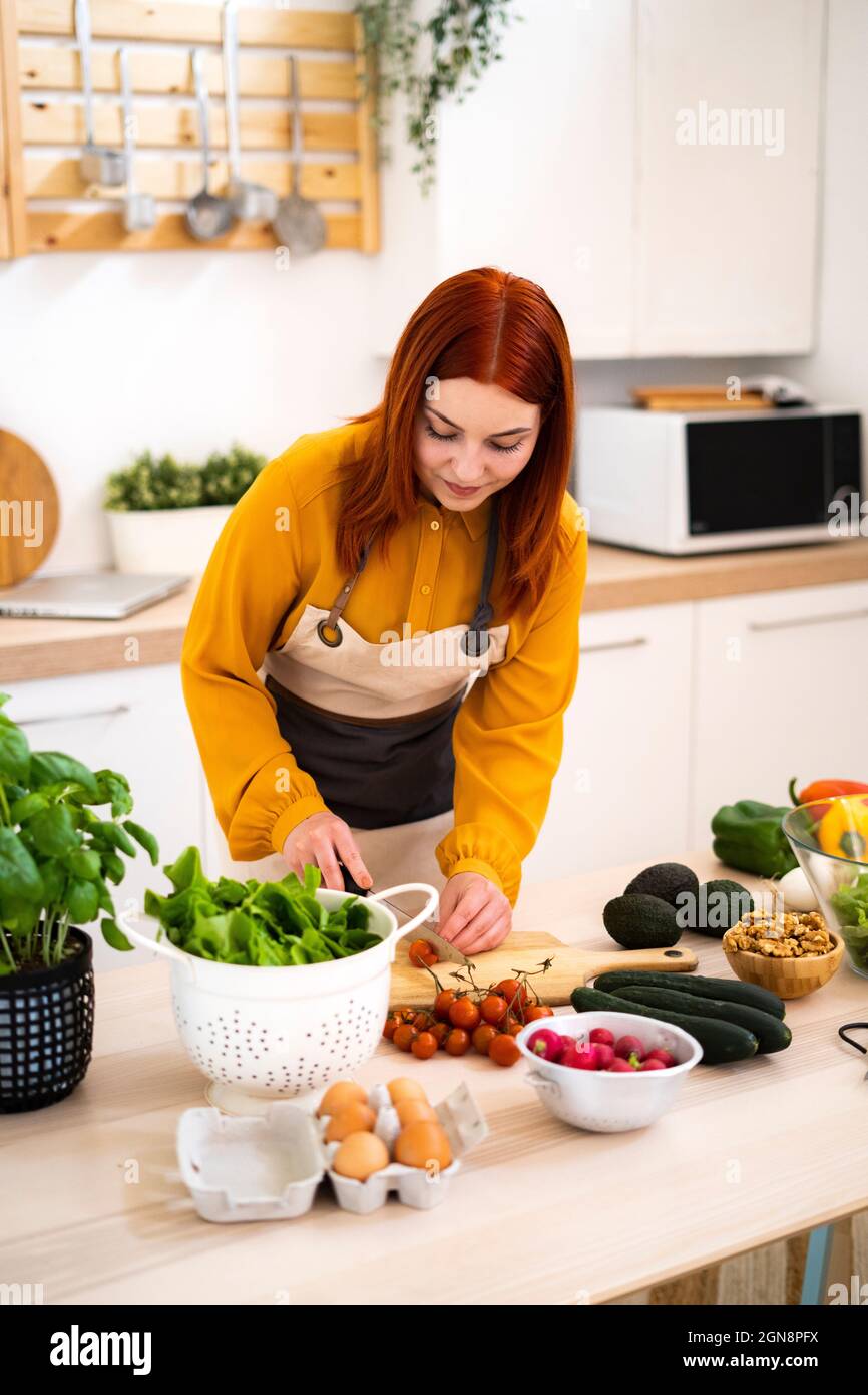 Woman preparing food while standing at table Stock Photo