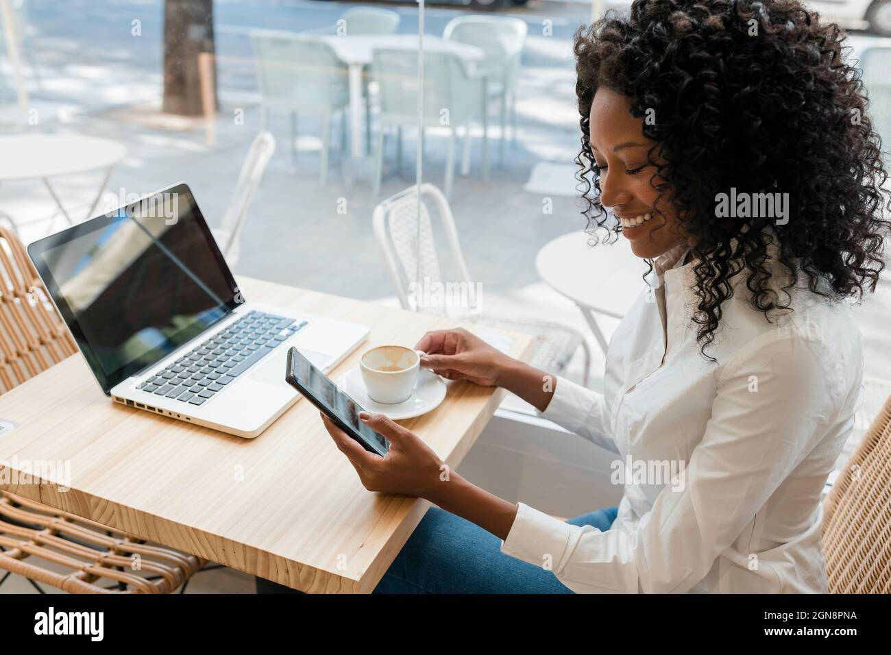 Female freelancer using mobile phone while sitting at cafe Stock Photo