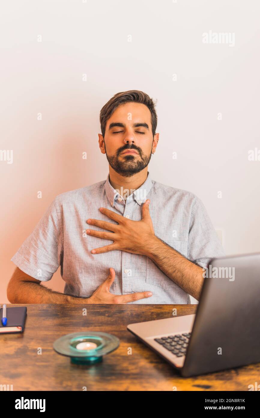 Male mental health professional showing breathing exercise during video call through laptop Stock Photo