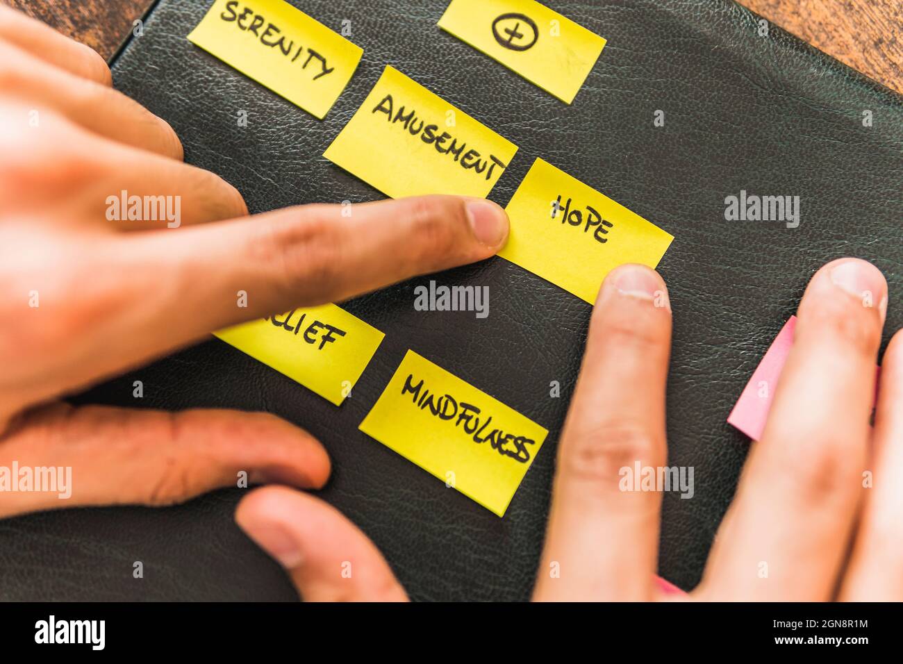 Male mental health expert putting yellow adhesive notes on black leather Stock Photo