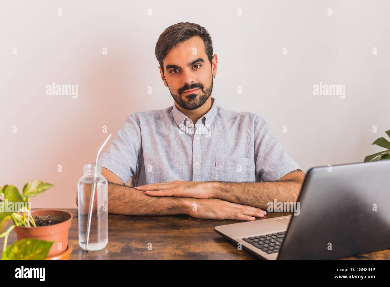 Man sitting with laptop and water bottle at desk Stock Photo