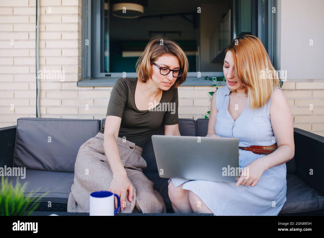 Female professionals using laptop while sitting on sofa Stock Photo