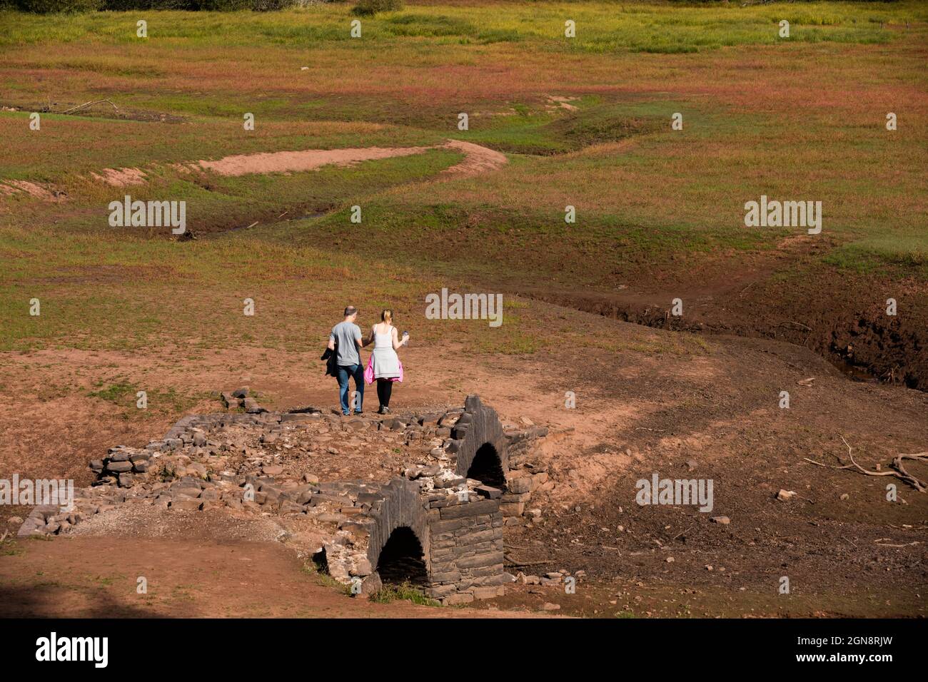 Llwyn Onn reservoir, Merthyr Tydfil, South Wales, UK.  23 September 2021.  UK weather:  Members of the public walk next to an old bridge, Pont Yr Daf, normally underwater.  Credit: Andrew Bartlett/Alamy Live News. Stock Photo