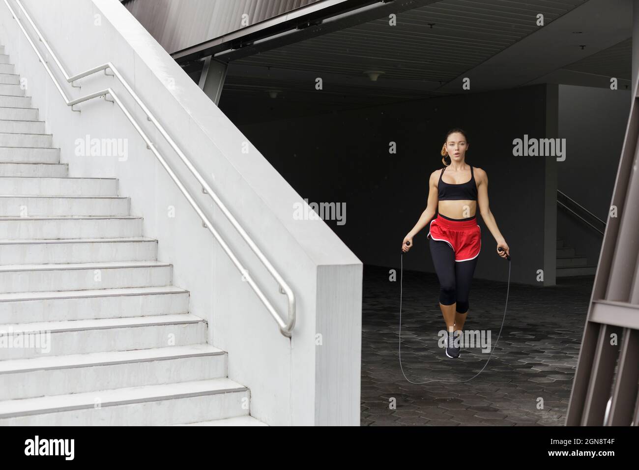 Young sportswoman jumping with rope at basement Stock Photo Alamy