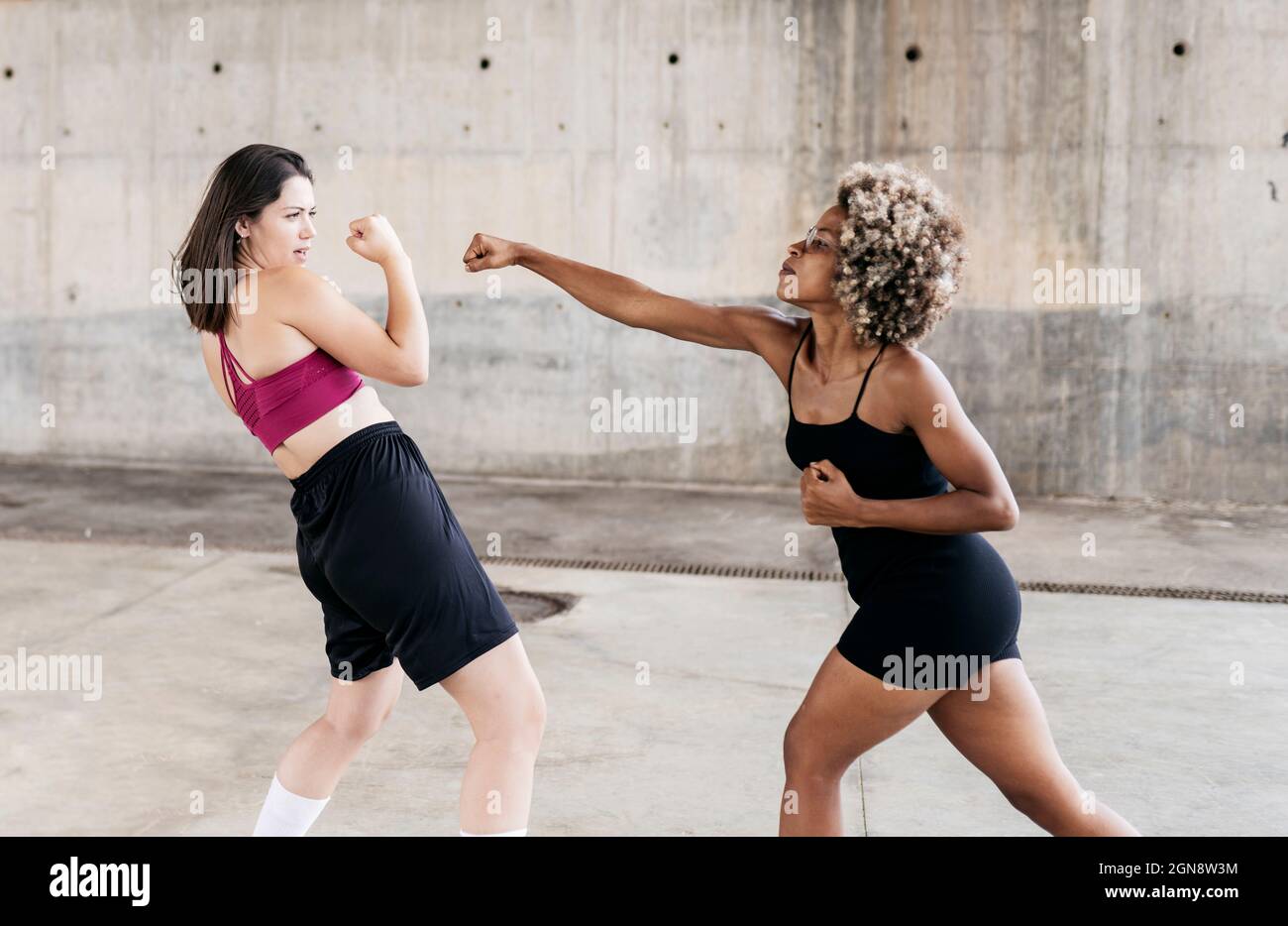 Multi-ethnic female friends punching while boxing Stock Photo