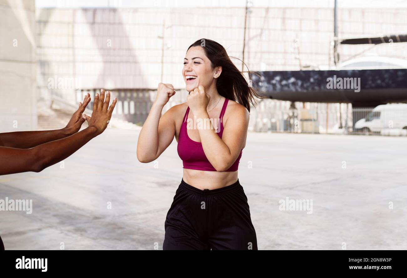 Cheerful woman doing boxing with female friend Stock Photo