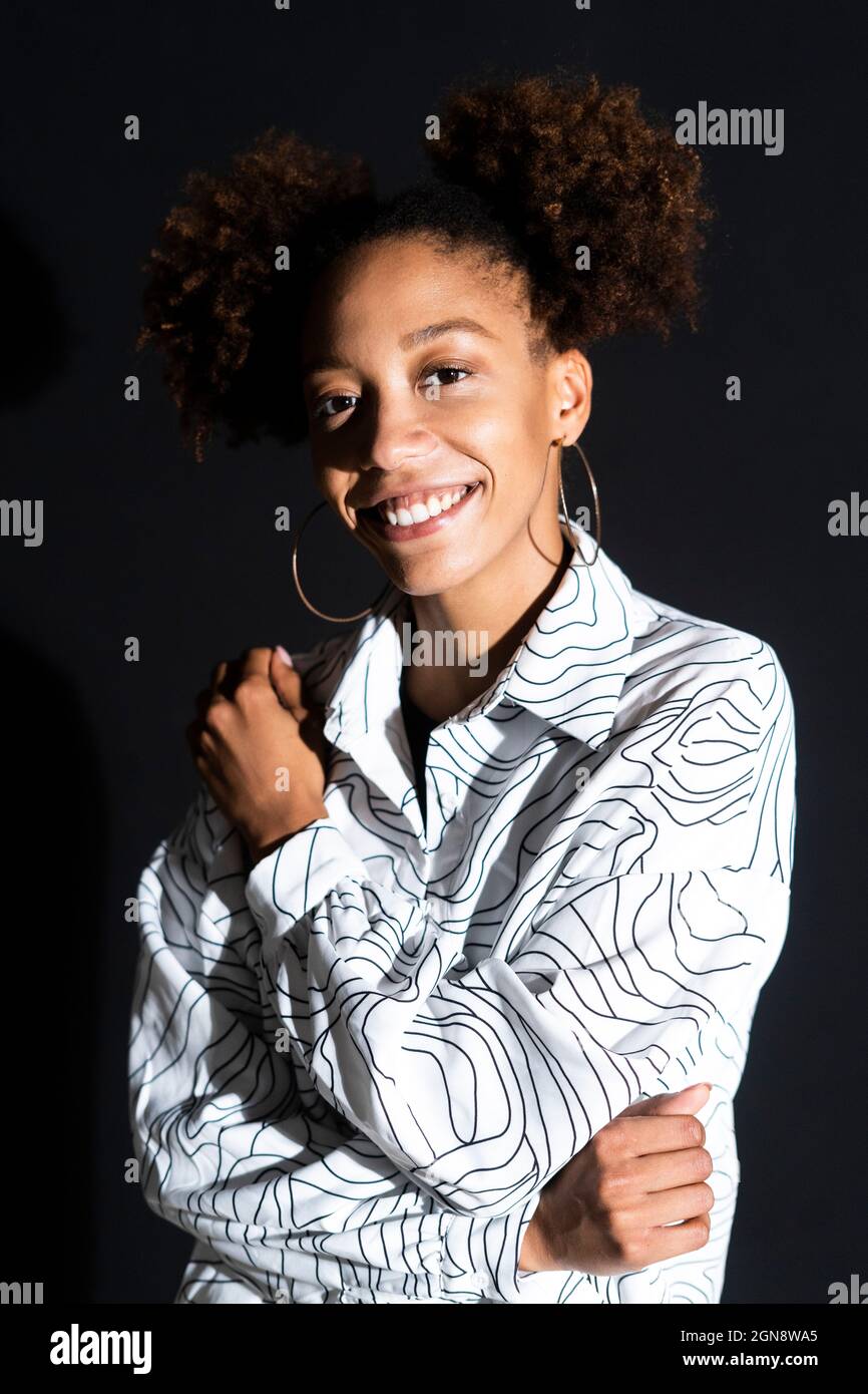 Afro woman smiling against black background Stock Photo - Alamy