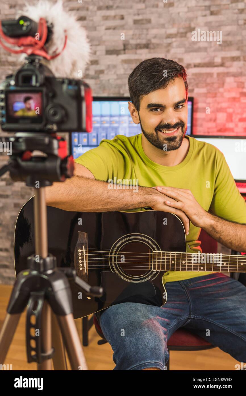 Smiling male guitarist recording in home video camera Stock Photo