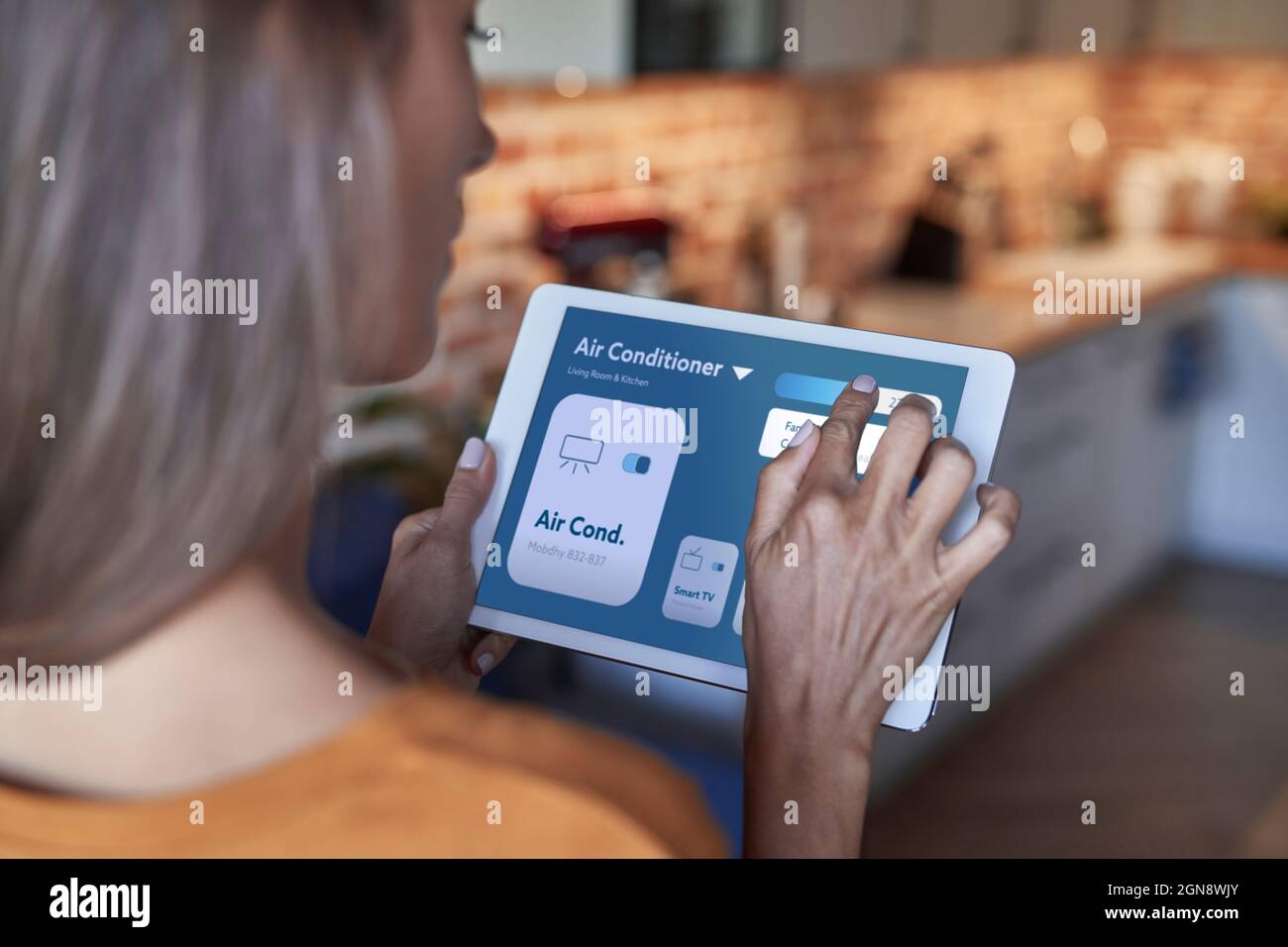 Woman adjusting air conditioner through digital tablet at home Stock Photo