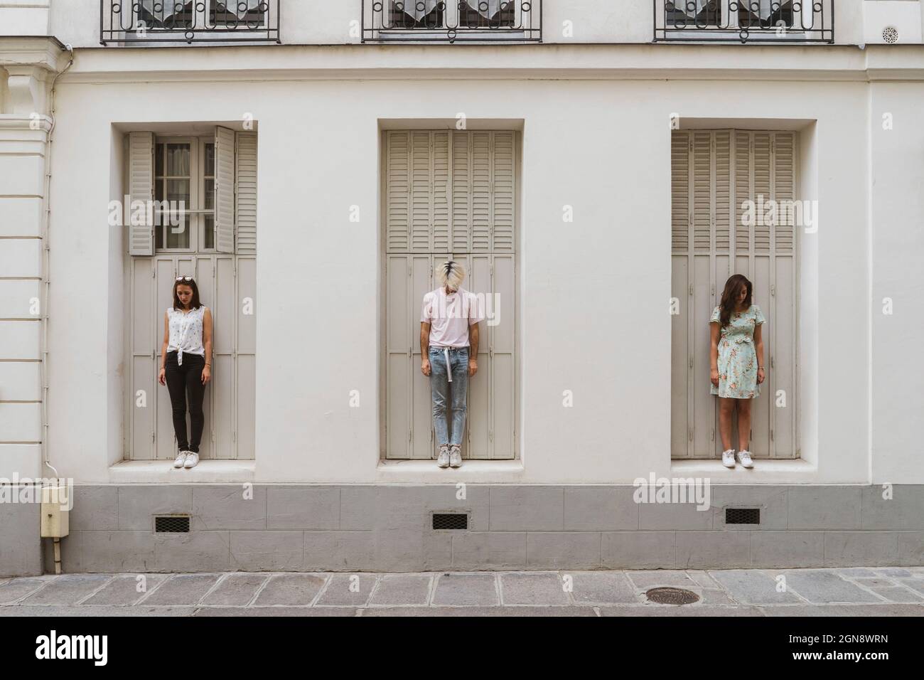 Young man and women looking down while standing in front of wall Stock Photo