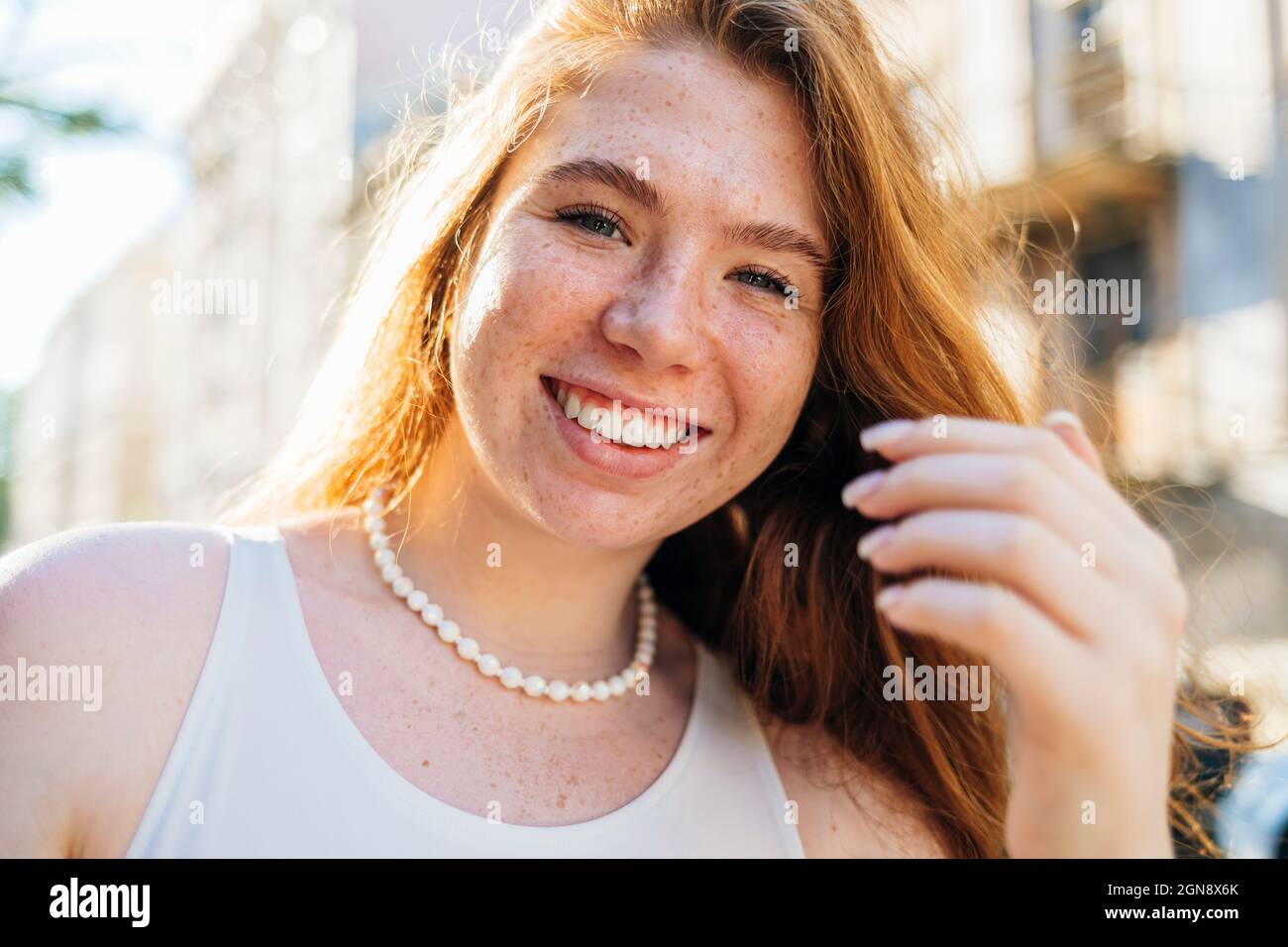 Happy young woman with freckles wearing pearl necklace Stock Photo