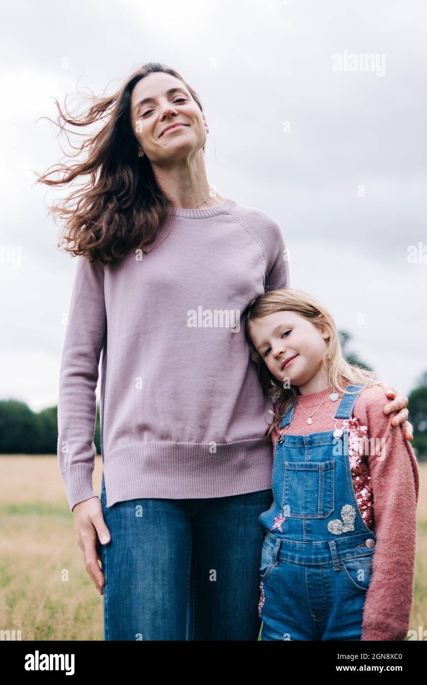 Smiling girl standing with woman at meadow Stock Photo