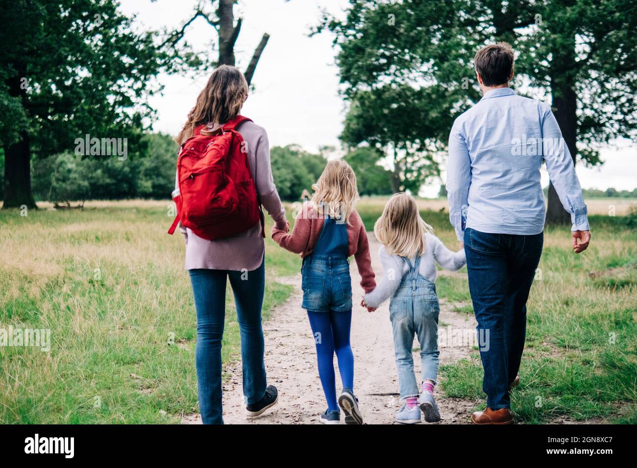 Family holding hands while walking together at park Stock Photo