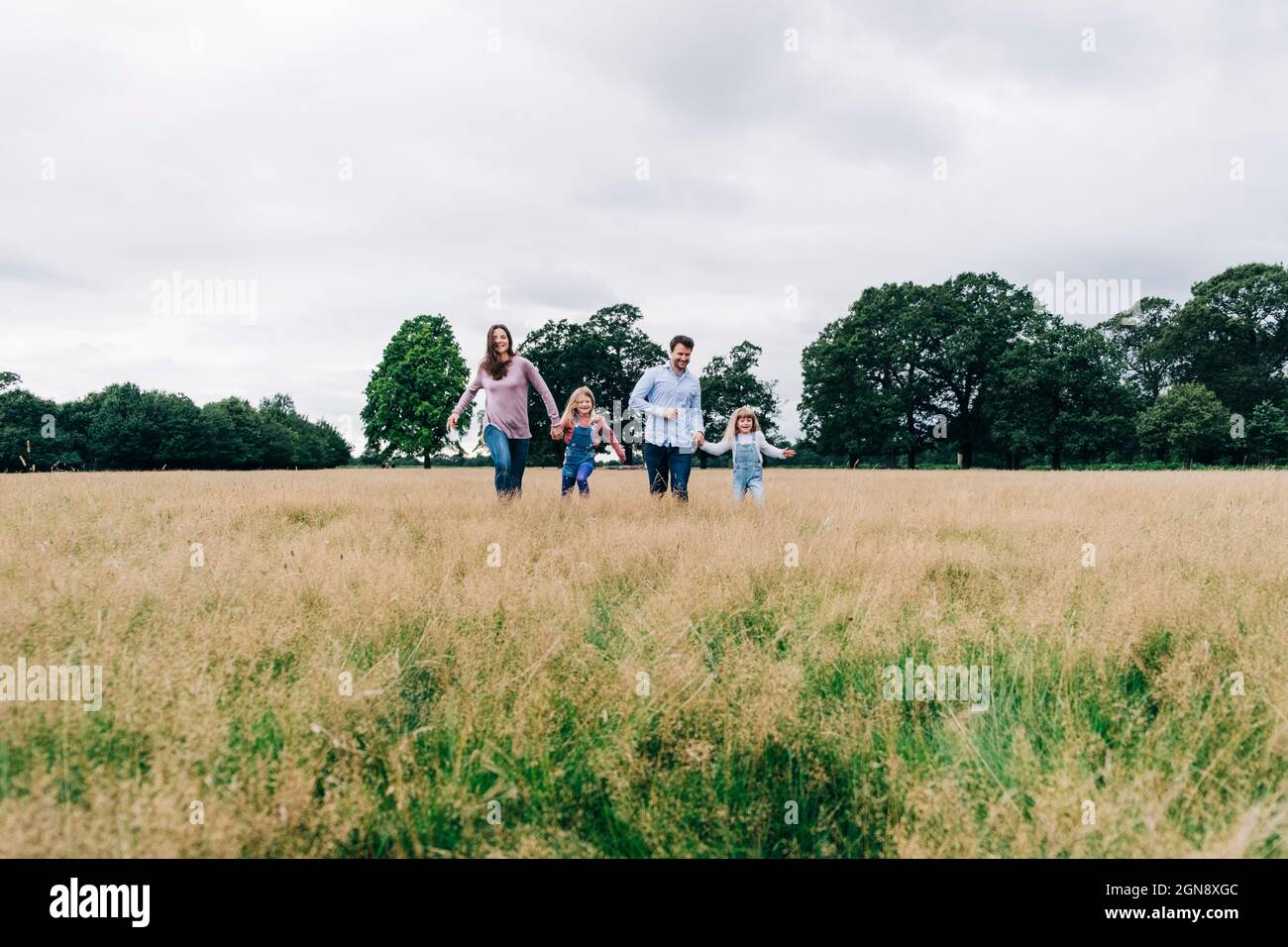 Carefree family holding hands while walking on grass Stock Photo