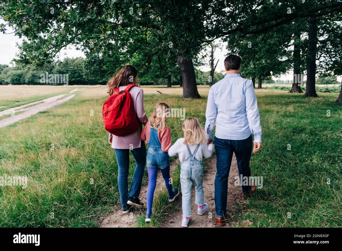 Daughters holding hands of parents while walking at park Stock Photo