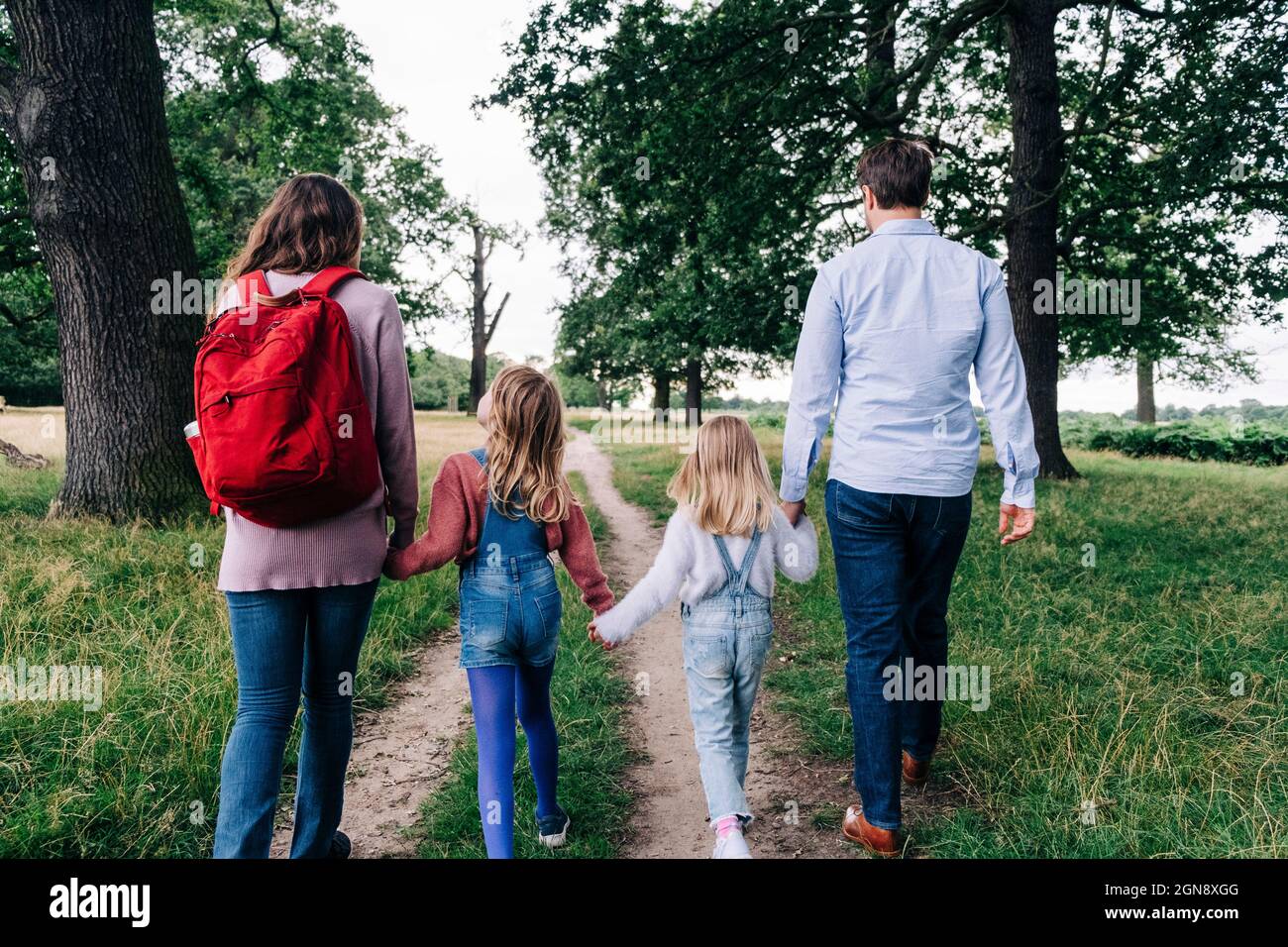 Family holding hands while walking on footpath at park Stock Photo