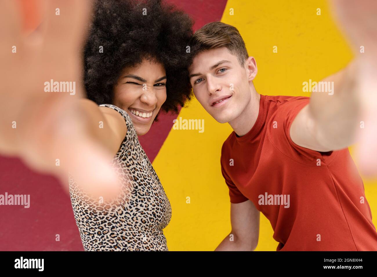 Multi-ethnic young couple gesturing in front of wall Stock Photo