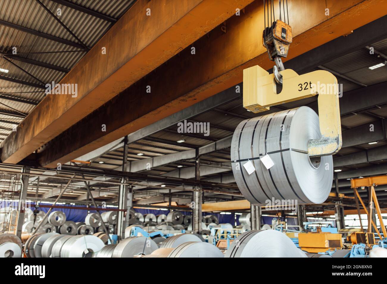 Overhead crane hook lifting rolled up metal sheet Stock Photo Alamy