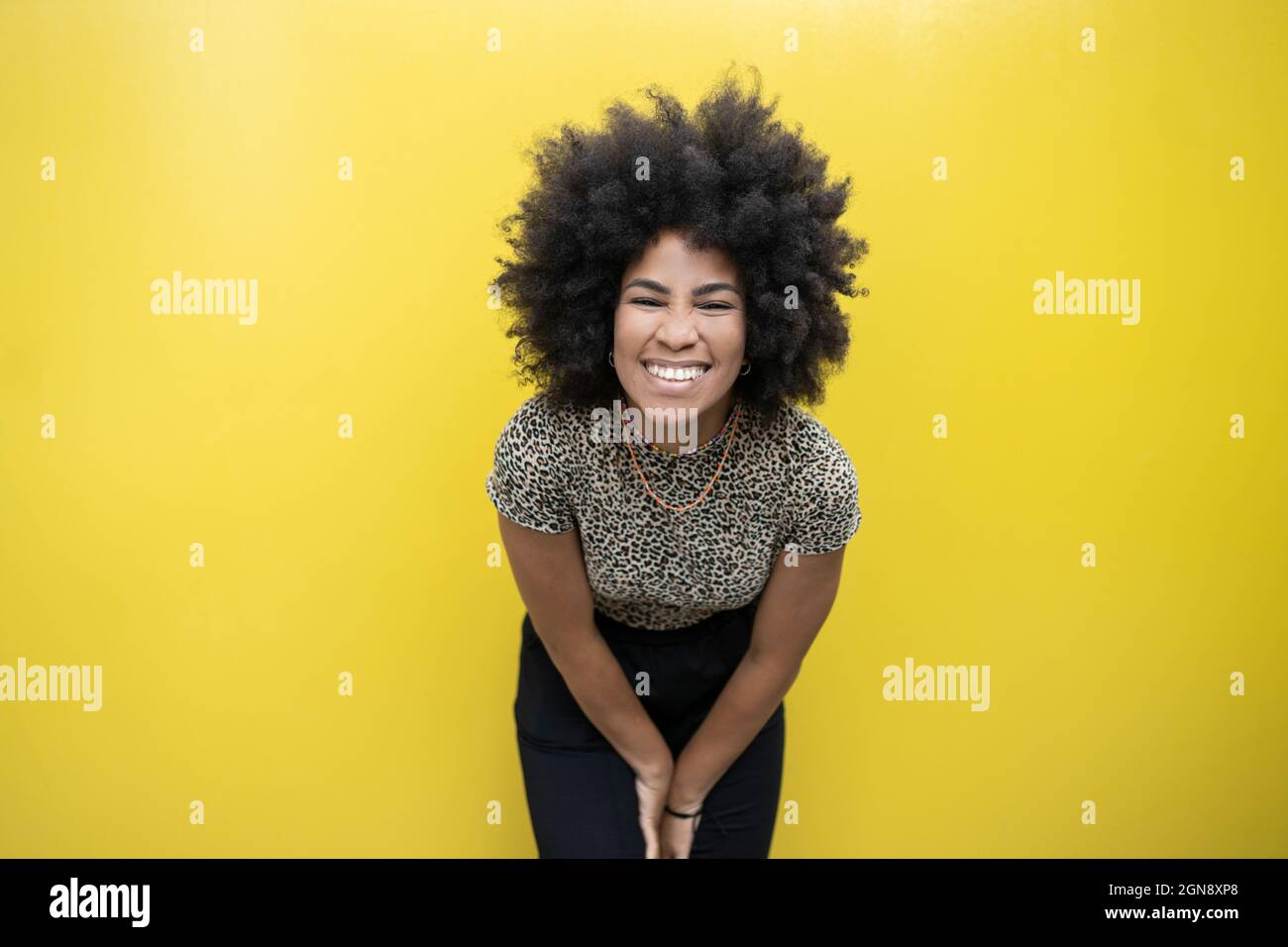 Afro woman smiling in front of yellow wall Stock Photo - Alamy