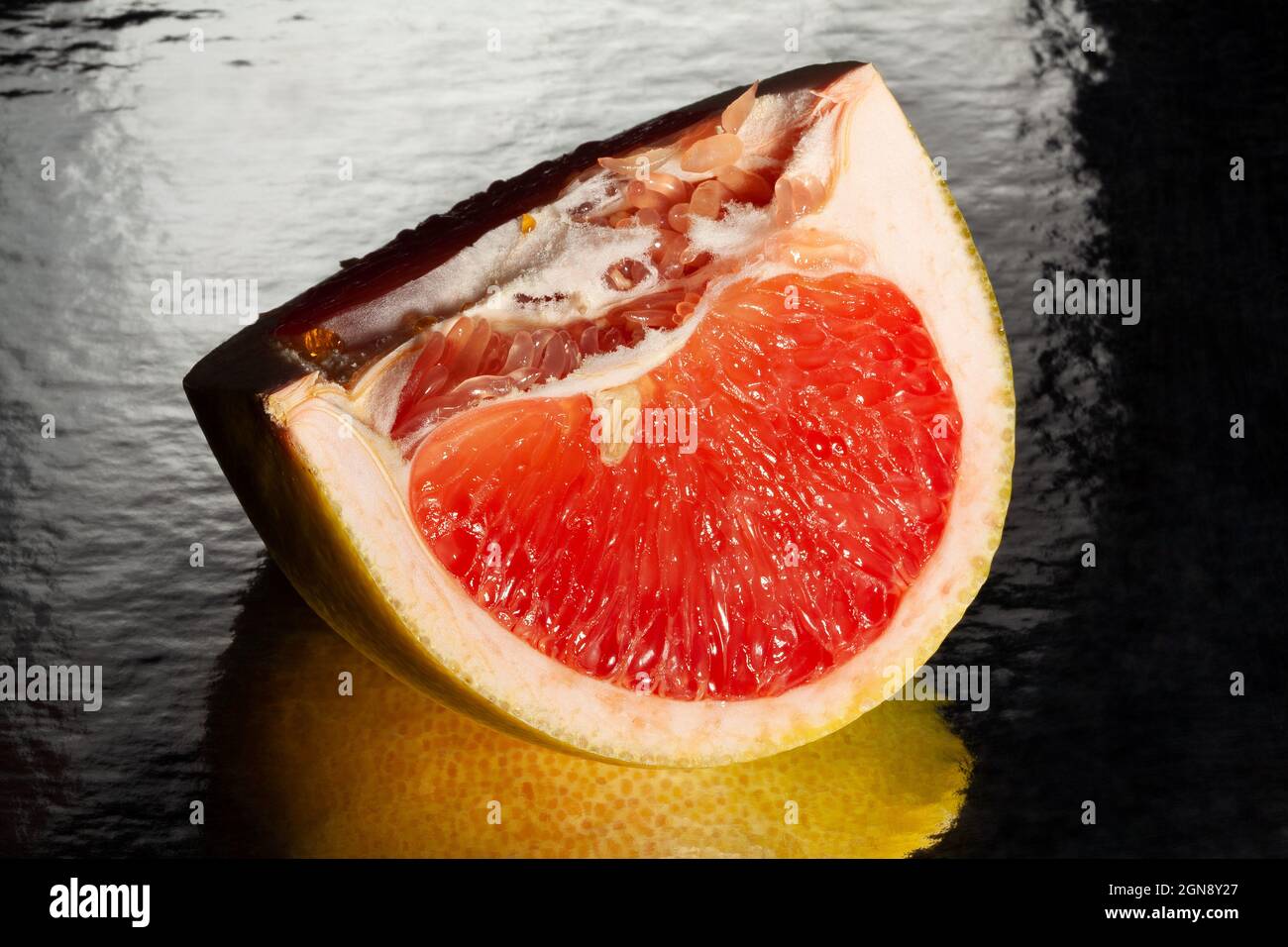 sliced mirrored yellow grapefruit on black background Stock Photo