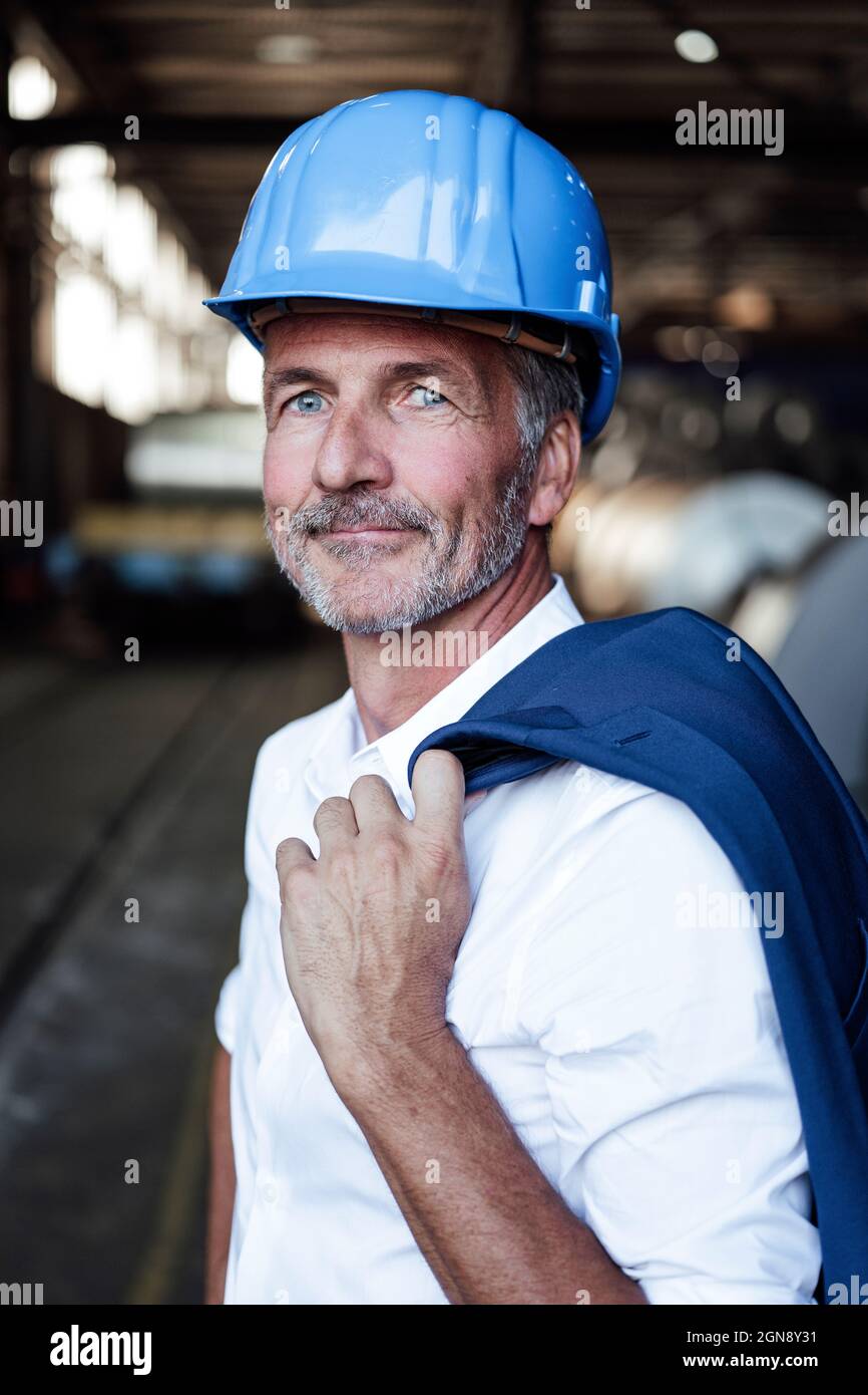 Male engineer with hardhat and blazer standing at warehouse Stock Photo ...