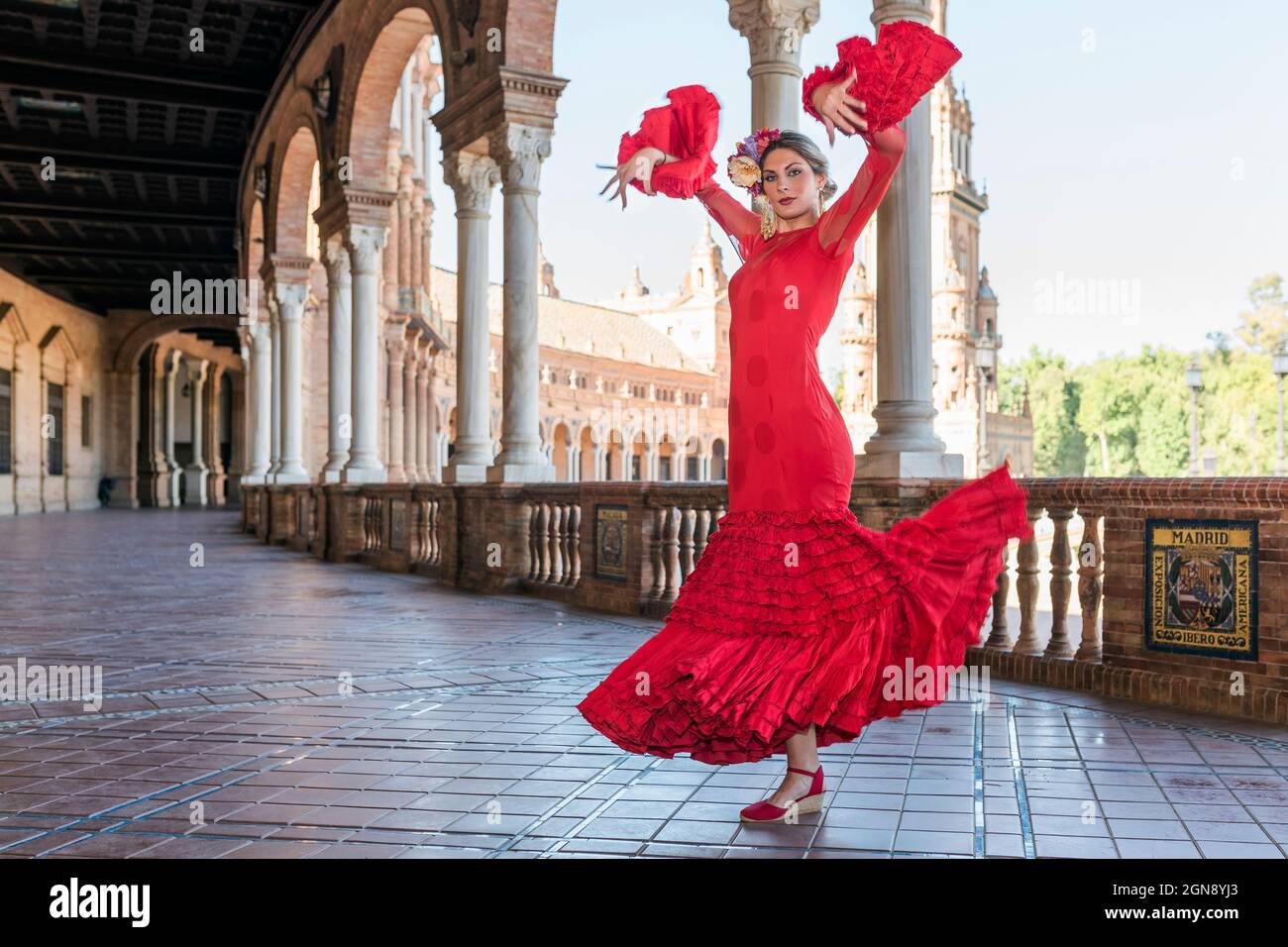 Female flamenco artist dancing with hands raised on walkway at Plaza De Espana, Seville, Spain Stock Photo