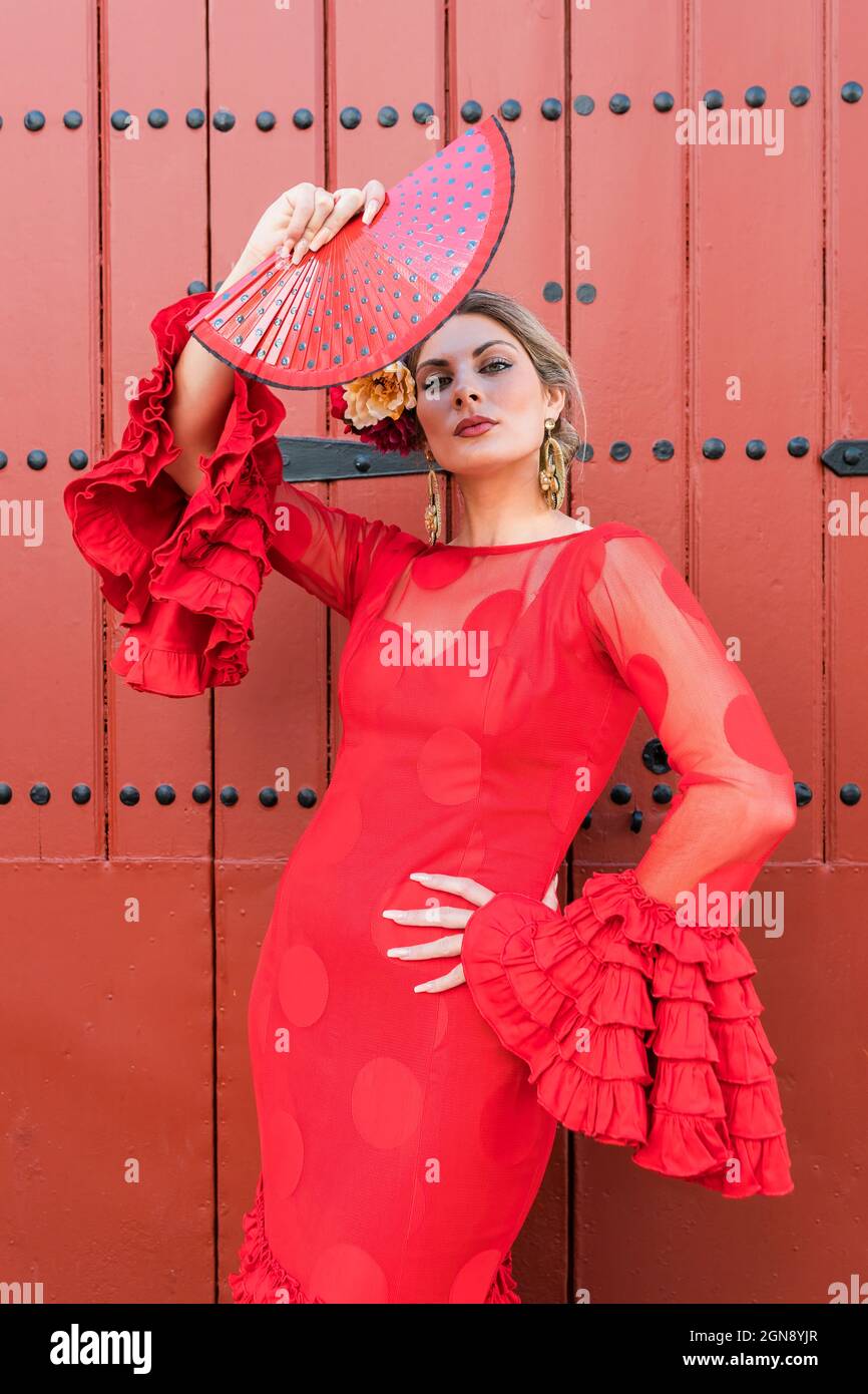 Confident female flamenco dancer holding hand fan in front of entrance Stock Photo