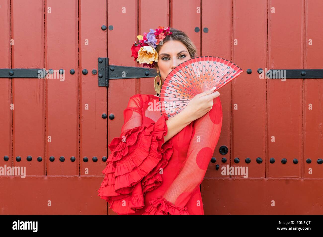 Female flamenco artist in traditional red dress holding hand fan Stock Photo