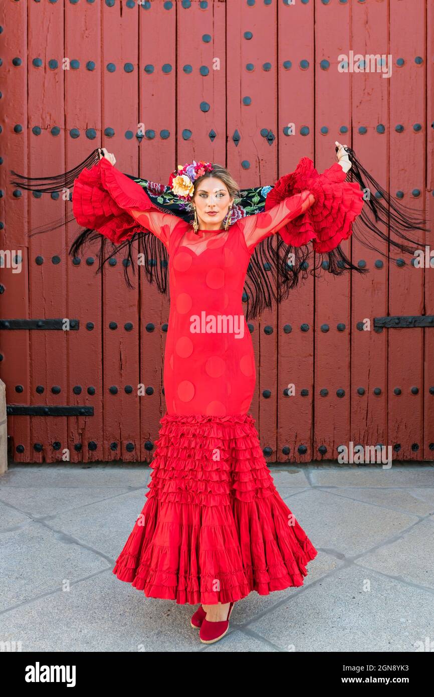 Female artist wearing traditional dress and shawl dancing in front of door Stock Photo