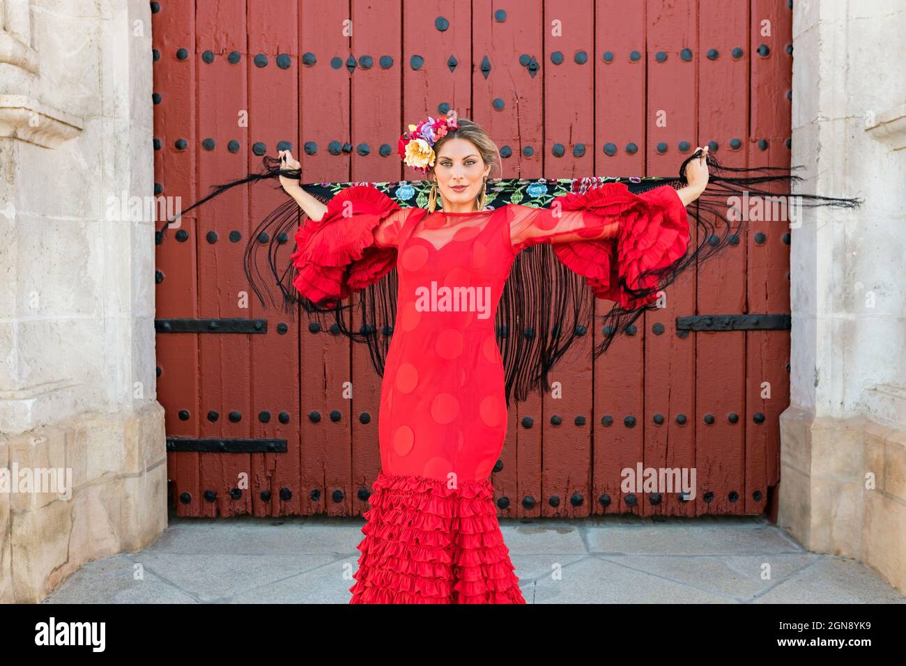 Female flamenco dancer holding shawl while spinning in front of door Stock Photo