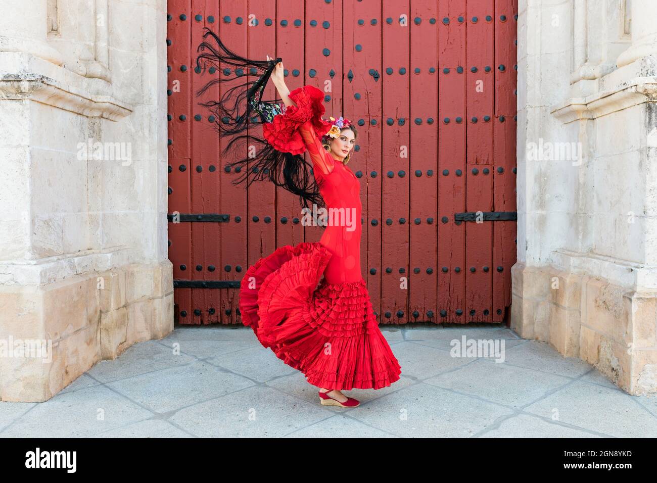 Female flamenco dancing with hands raised by door Stock Photo