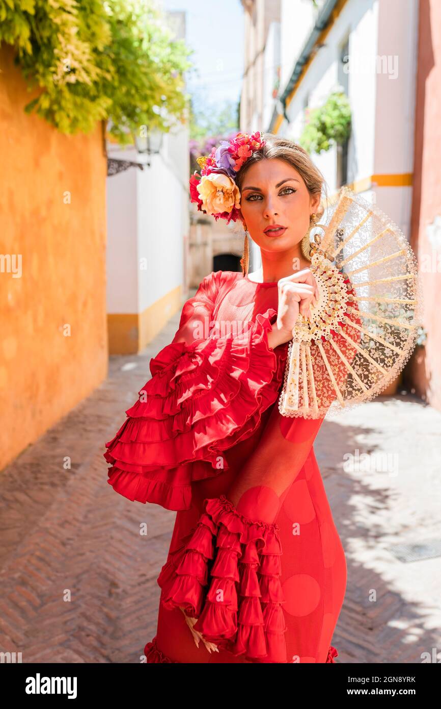 Female artist with traditional dress and hand fan standing at alley Stock Photo