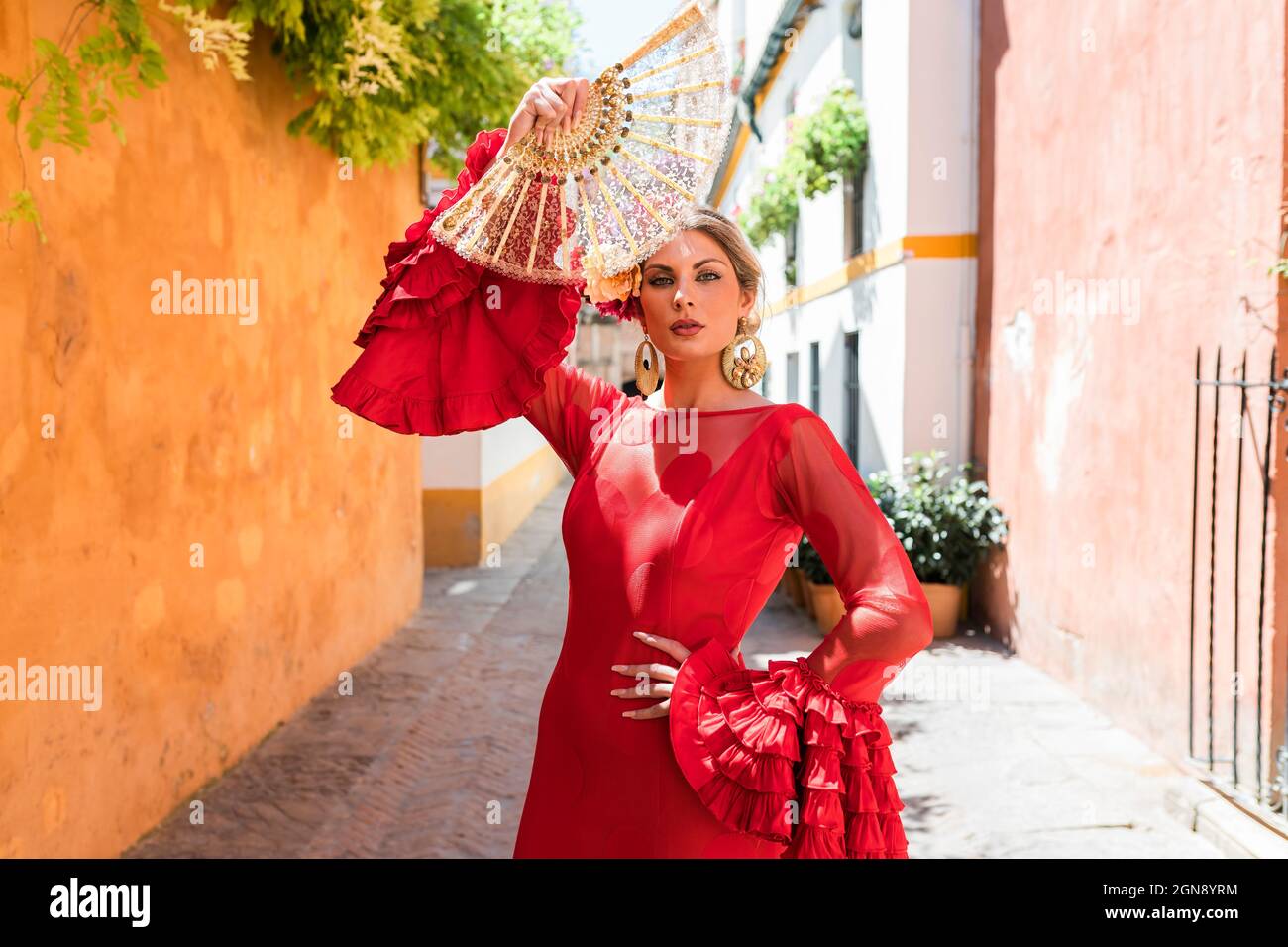Female flamenco artist with hand fan standing at alley Stock Photo