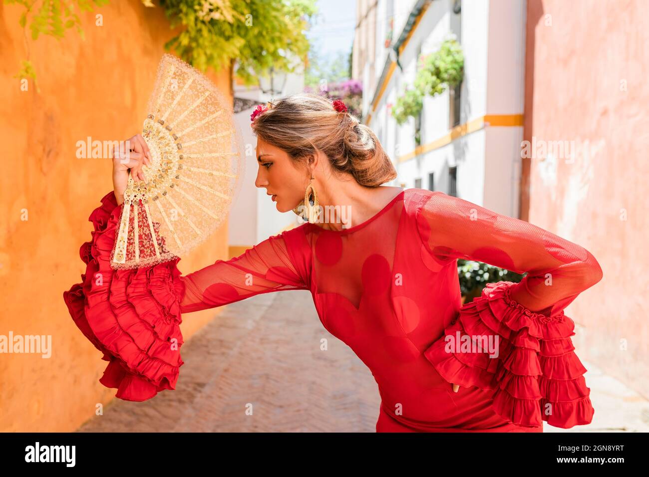 Female flamenco dancer with hand fan dancing at alley Stock Photo