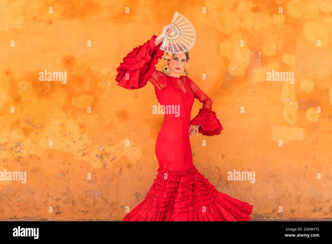 Female flamenco dancer with hand fan standing in front of wall Stock Photo