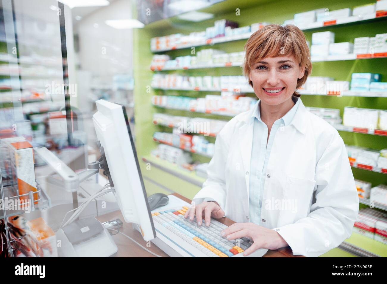 Smiling female pharmacist working on computer at medical store Stock Photo